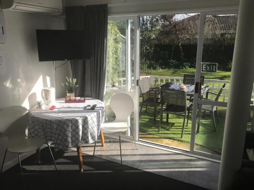 a dining room with a table and chairs and a patio at Sandy Feet Accommodation in Christchurch