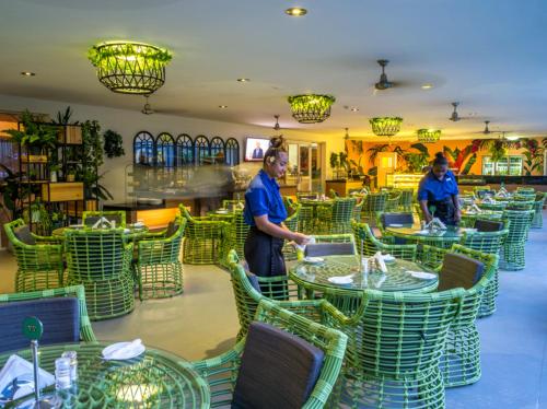 two men standing in a restaurant with tables and chairs at Heritage Park Hotel in Honiara