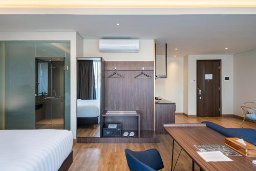 a bedroom with a bed and a desk and a kitchen at Luminor Hotel Jakarta Kota By WH in Jakarta