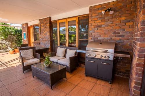 a patio with a stove and a brick wall at Ainslie Manor Guest House in Redcliffe