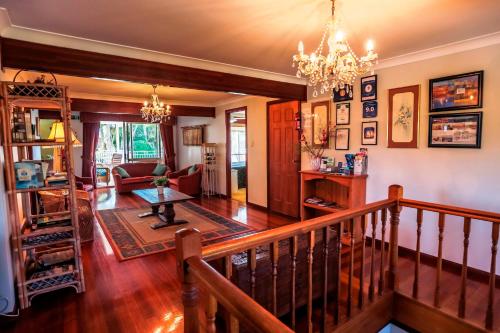 a living room with a staircase and a chandelier at Ainslie Manor Guest House in Redcliffe