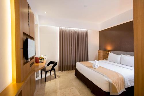a hotel room with a bed and a flat screen tv at LYNN Hotel by Horison in Yogyakarta