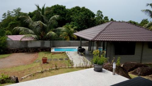 a house with a roof and a swimming pool at Eco Lodge Self-Catering in Mahe