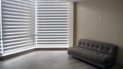 a living room with a couch and a large window at Edificio Tofino in Quito