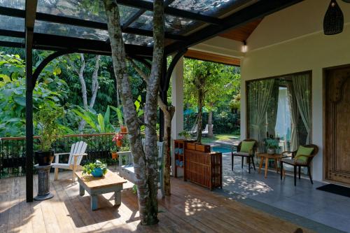 eine Terrasse mit einem Tisch, Stühlen und einem Baum in der Unterkunft Plataran Borobudur in Borobudur