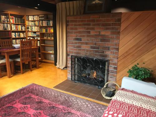 a fireplace in a living room with a table and chairs at Karori Cottage in Wellington