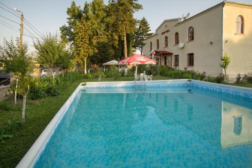 a swimming pool in front of a house at Hotel Kakhaberi in Tʼetʼri Tsqaro