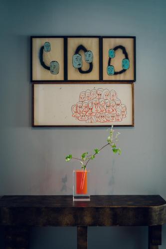 a vase sitting on a wooden table with three pictures at node hotel in Kyoto