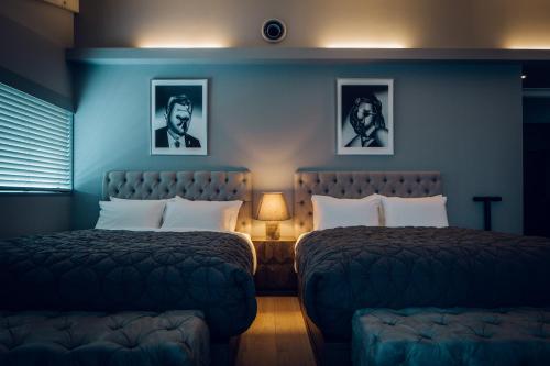 two beds in a room with blue walls at node hotel a Member of Design Hotels in Kyoto