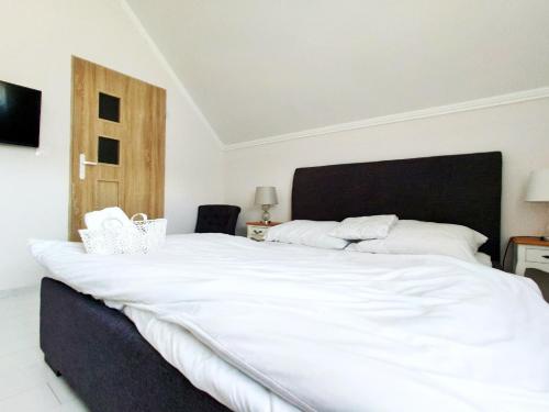 a bedroom with a large white bed with a black headboard at B&B Źródlana 46 in Olszyna
