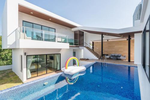 a villa with a swimming pool and a house at Movenpick Residences 3-Bedroom Pool Villa Beach Access, Na Jomtien Pattaya in Na Jomtien