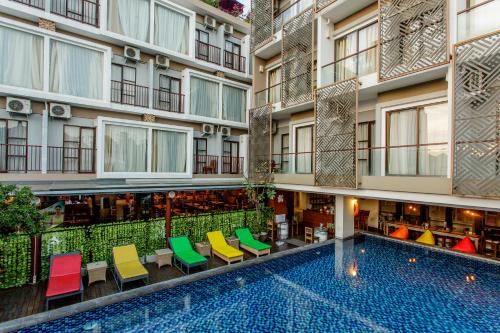 an apartment building with a swimming pool and colorful chairs at Horison Ultima Seminyak Bali - CHSE Certified in Seminyak