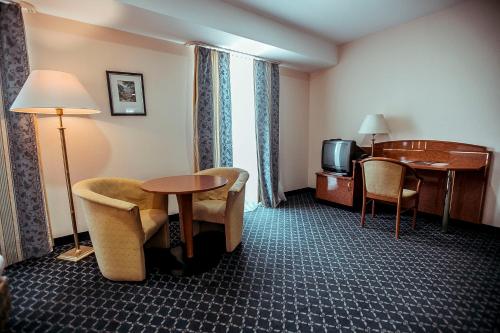 a hotel room with a table and chairs and a television at Shodlik Palace in Tashkent