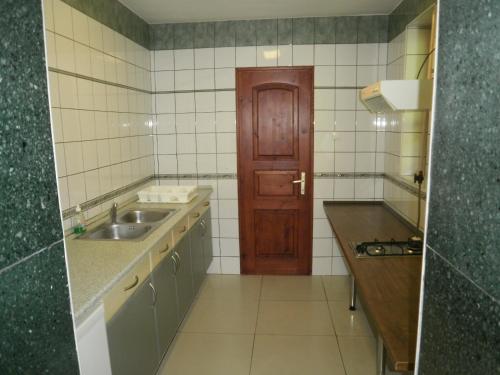 a kitchen with a sink and a wooden door at Palatinus Apartmanok in Keszthely