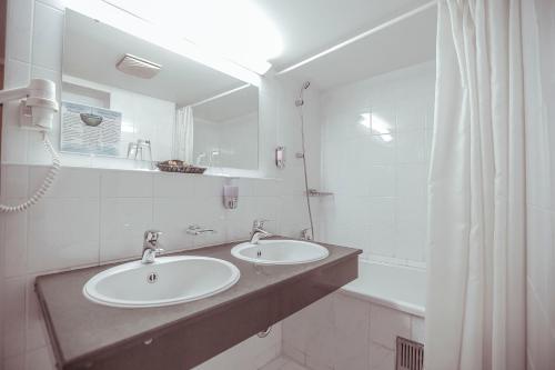 La salle de bains est pourvue de 2 lavabos, d'un miroir et d'une baignoire. dans l'établissement Shodlik Palace, à Tachkent