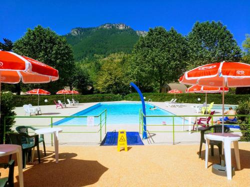 a swimming pool with tables and umbrellas and a pool at Camping le Pré Morjal in Ispagnac