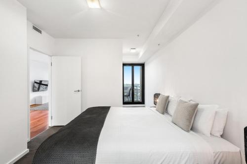 a white bedroom with a large white bed with pillows at Melbourne Holiday Apartments Flinders Wharf in Melbourne