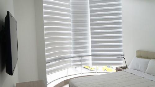 a bedroom with a large window with white blinds at Edificio Tofino in Quito