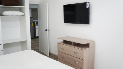 a bedroom with a bed and a tv on a wall at Edificio Tofino in Quito