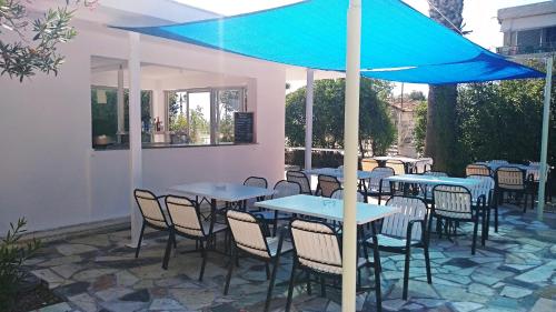 a patio area with chairs, tables and umbrellas at Nireus Hotel in Nea Makri