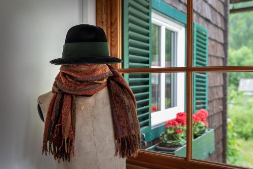a mannequin wearing a hat and scarf next to a window at B&B Haus Hemetzberger in Hallstatt