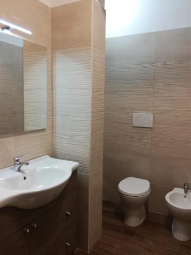 a bathroom with a sink and a toilet and a mirror at La casa di Mela in Leverano