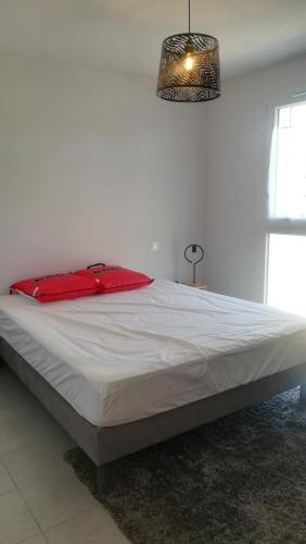 une chambre avec un grand lit avec un oreiller rouge dans l'établissement Links, à Mimizan