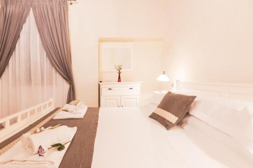 a white bedroom with a large white bed and a window at Albergo Giardino in Montalcino