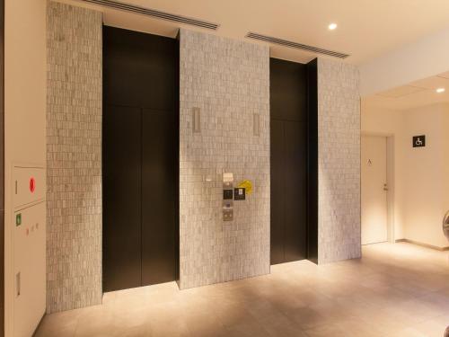 a room with black doors and tile walls at Henn na Hotel Tokyo Ginza in Tokyo