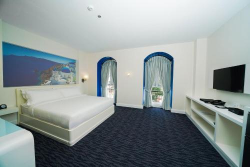 a hotel room with a bed and a flat screen tv at Hotel Carlito Tagaytay in Tagaytay