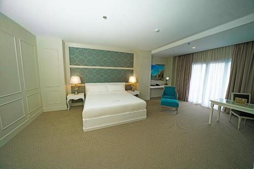 a bedroom with a white bed and a blue chair at Hotel Carlito Tagaytay in Tagaytay
