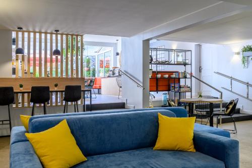 a living room with a blue couch and yellow pillows at Citadines Wilson Toulouse in Toulouse