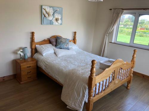 a bedroom with a wooden bed and a window at Spanish Point Armada Getaway in Spanish Point