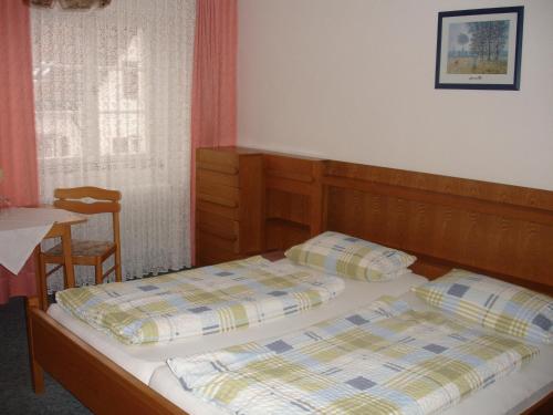 1 Schlafzimmer mit 2 Betten, einem Tisch und einem Fenster in der Unterkunft Gästehaus Sparenberg in Bad Krozingen