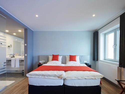 a bedroom with a large bed with red pillows at Amel Mitte Bed & Breakfast in Amblève