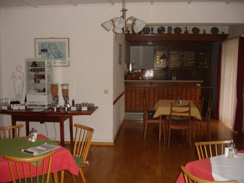 a dining room with tables and chairs and a kitchen at Gästehaus Sparenberg in Bad Krozingen