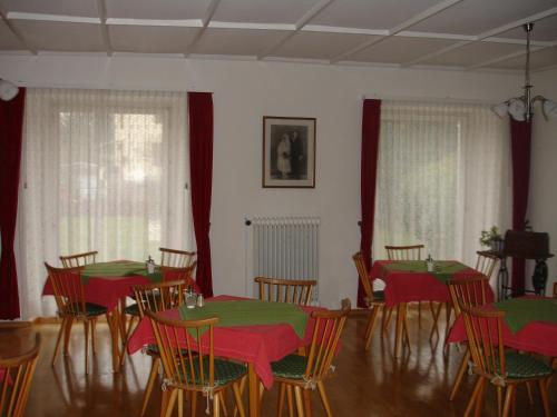 jadalnia z czerwonymi i zielonymi stołami i krzesłami w obiekcie Gästehaus Sparenberg w mieście Bad Krozingen
