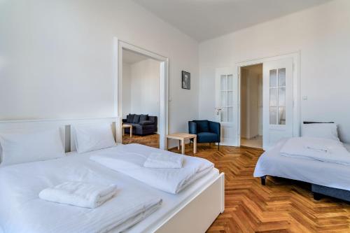 a white bedroom with two beds and a blue chair at Avantguard Apartments in Prague
