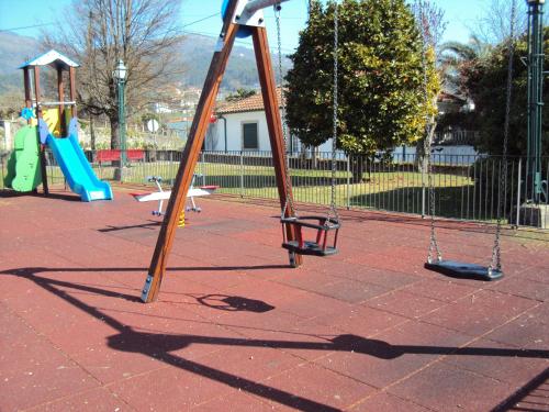 a playground with three swings and a slide at Casa do Mosteiro de Refoios do Lima in Ponte de Lima