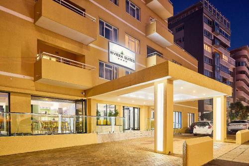 a large yellow building with a sign on it at First Group Riviera Suites in Cape Town