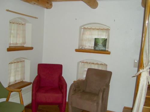 a room with two chairs and two windows at Jabjemööh's Huus in Greetsiel