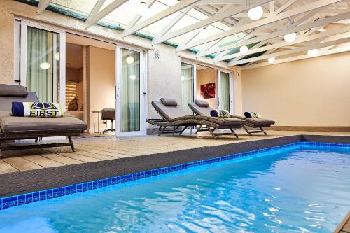 una piscina en una casa con sillas y mesa en First Group Riviera Suites, en Ciudad del Cabo