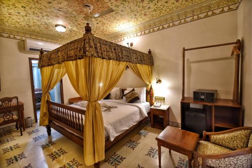 1 dormitorio con cama con dosel y cortinas amarillas en Nirbana Palace - A Heritage Hotel and Spa, en Jaipur