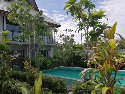 a swimming pool in front of a house with trees at JR Place in Klong Muang Beach