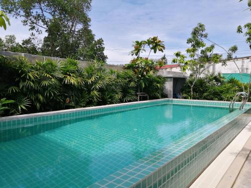 a swimming pool at a resort with trees and plants at JR Place in Klong Muang Beach