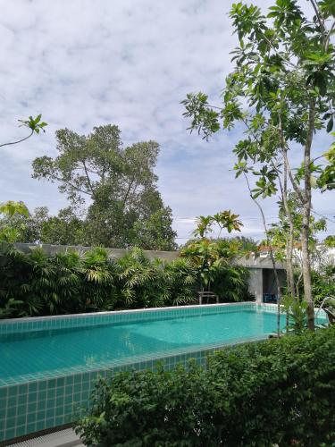 a swimming pool in front of a building with trees at JR Place in Klong Muang Beach