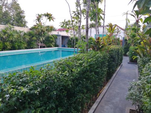 a swimming pool in front of a building with trees at JR Place in Klong Muang Beach