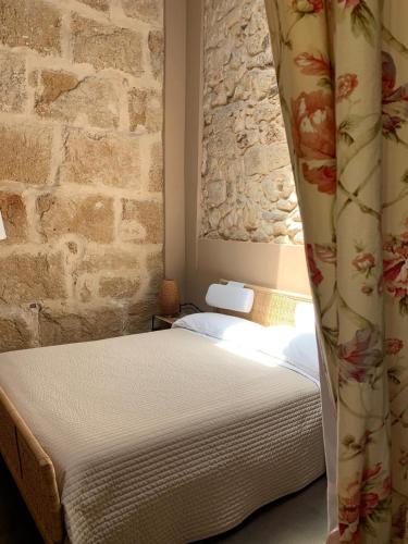 a bedroom with a bed and a stone wall at Chiusa Di Carlo Agriturismo in Avola