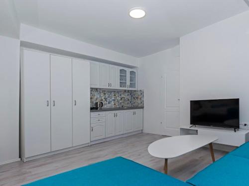 a kitchen with white cabinets and a table and a tv at Casa di VaLL City Apartments in Ohrid