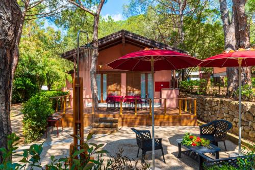 una casa con 2 sombrillas rojas y un patio en Camping Lacona Pineta, en Capoliveri